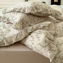 Floral patterned bedding with ruffles on a bed in a bedroom setting.